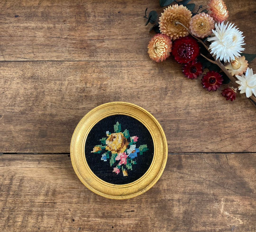 Broderie encadrée sur fond noir cadre rond doré