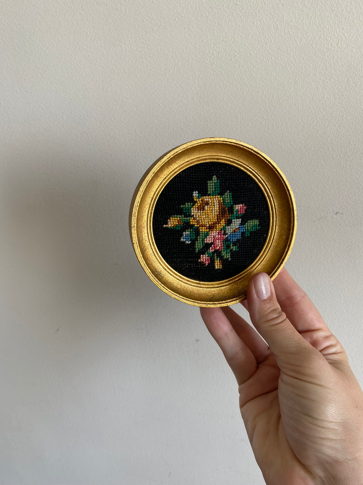 Broderie encadrée sur fond noir cadre rond doré
