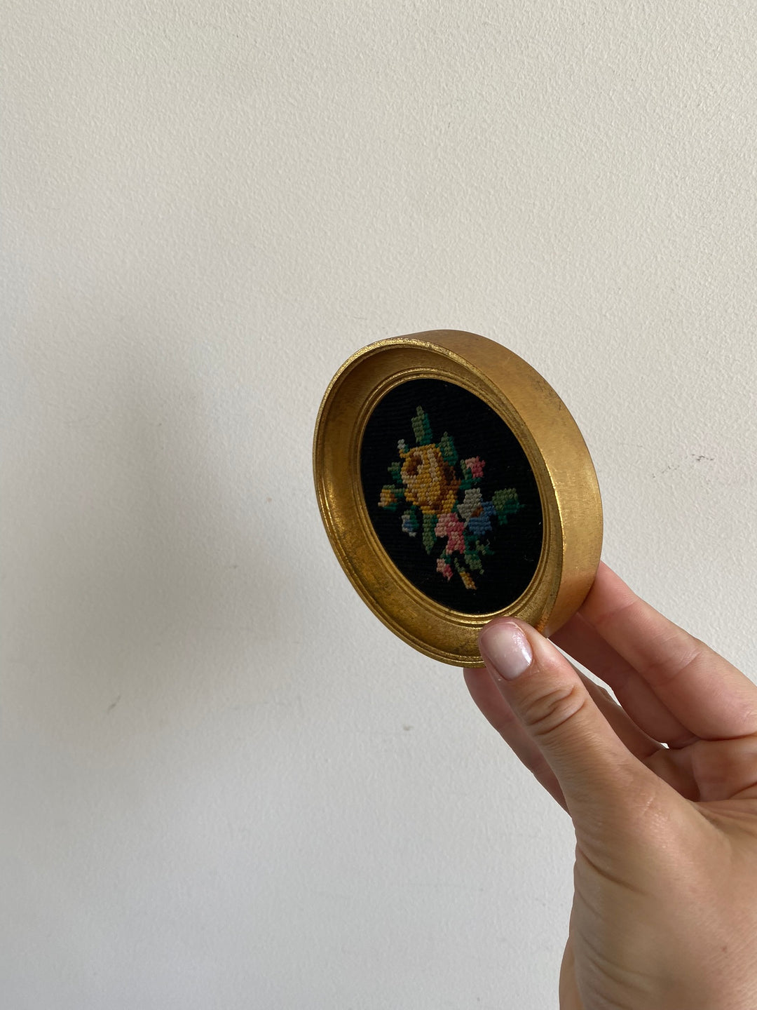 Broderie encadrée sur fond noir cadre rond doré