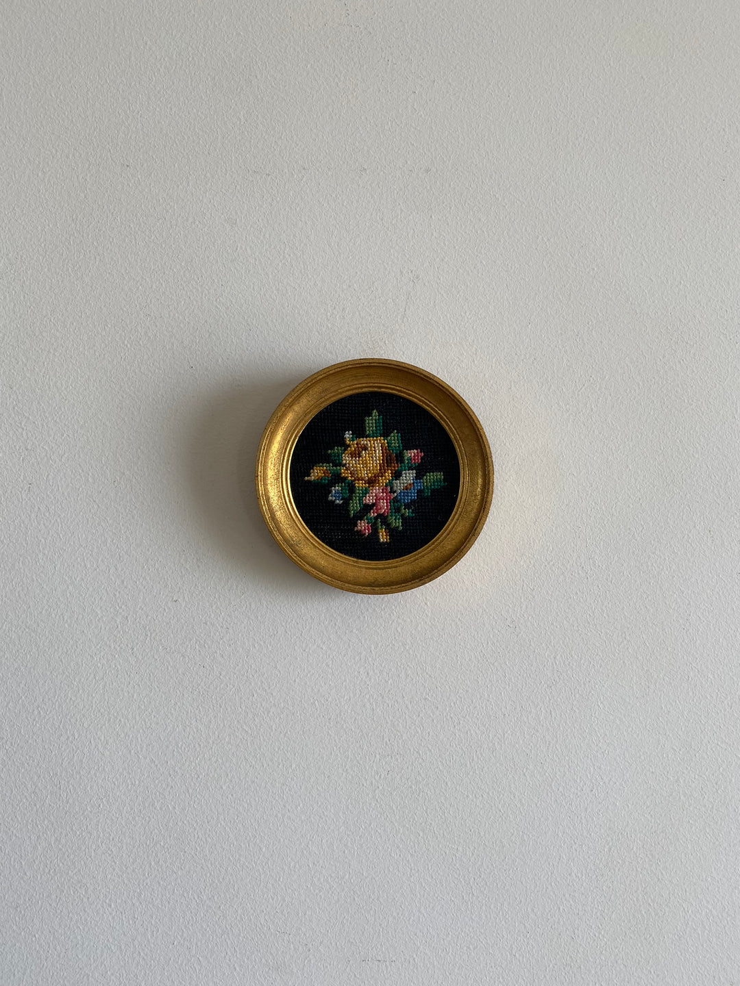 Broderie encadrée sur fond noir cadre rond doré