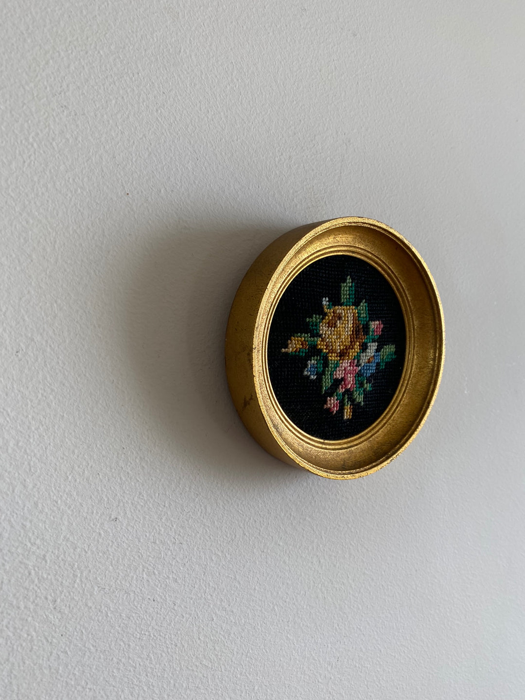 Broderie encadrée sur fond noir cadre rond doré