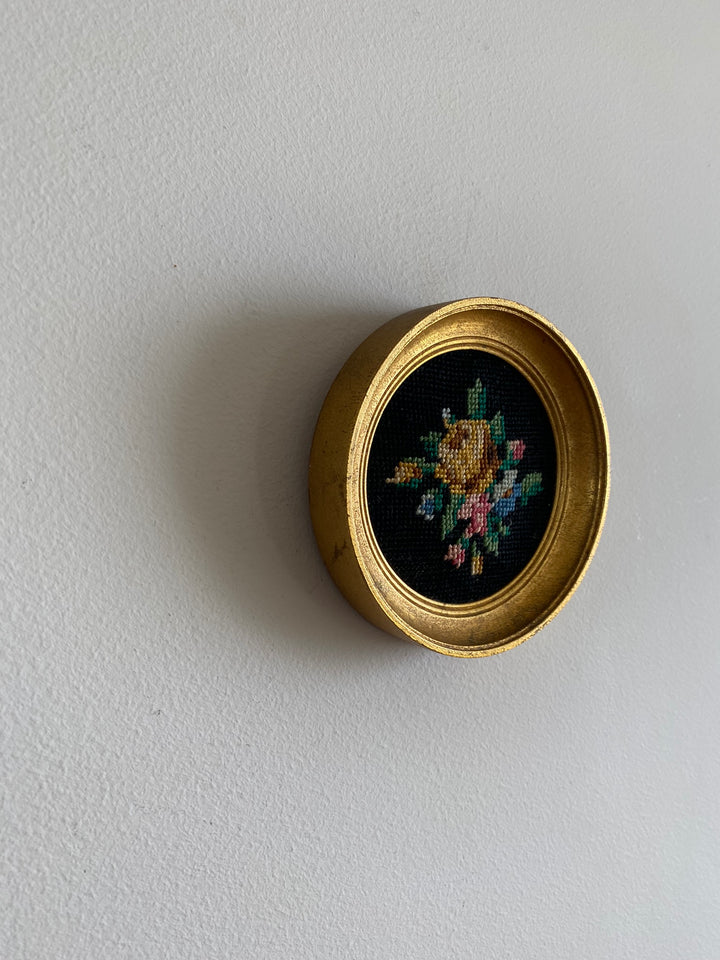 Broderie encadrée sur fond noir cadre rond doré