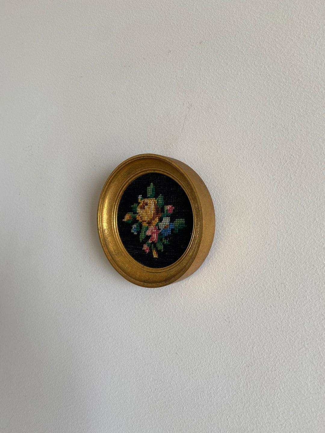 Broderie encadrée sur fond noir cadre rond doré