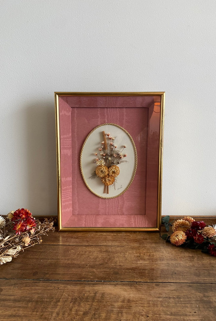 Fleurs séchées encadrées sur fond rose en tissu