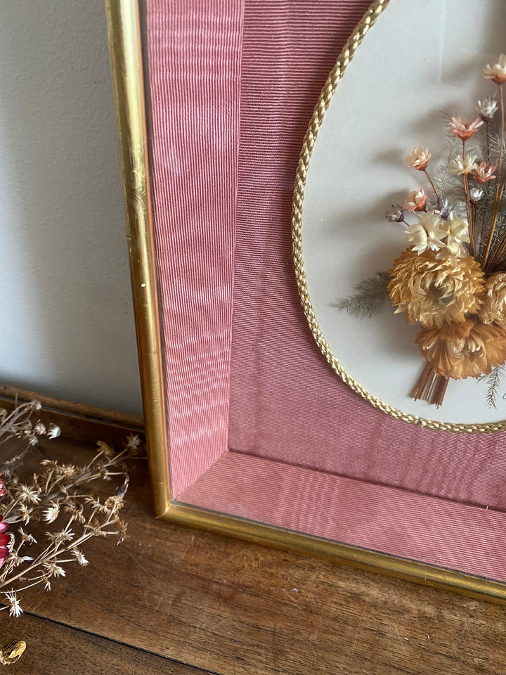 Fleurs séchées encadrées sur fond rose en tissu
