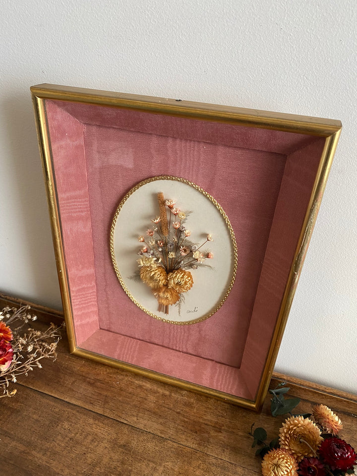 Fleurs séchées encadrées sur fond rose en tissu