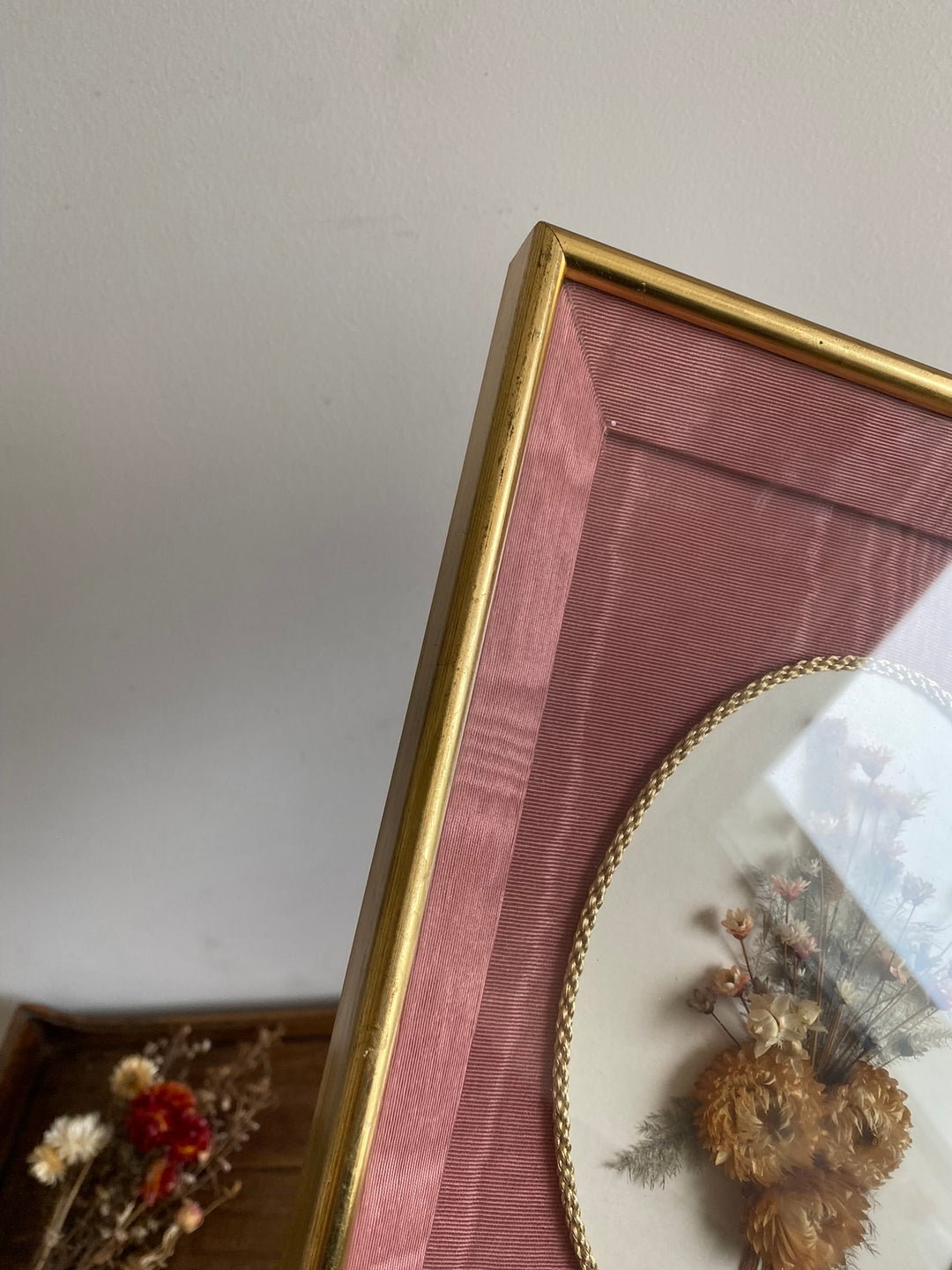 Fleurs séchées encadrées sur fond rose en tissu