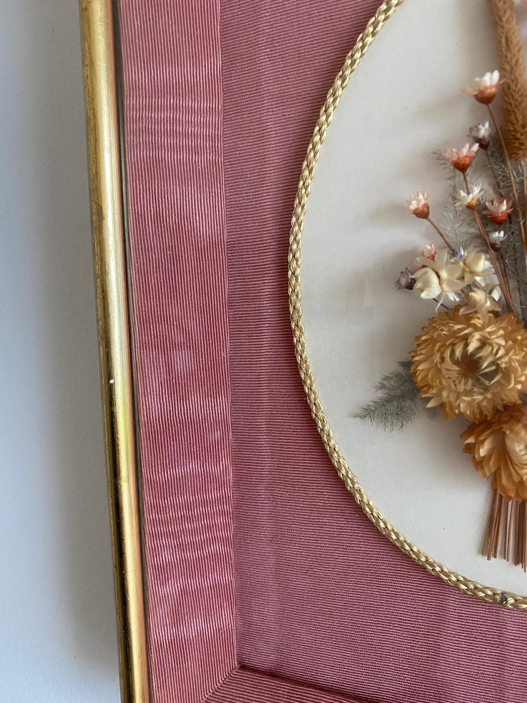 Fleurs séchées encadrées sur fond rose en tissu