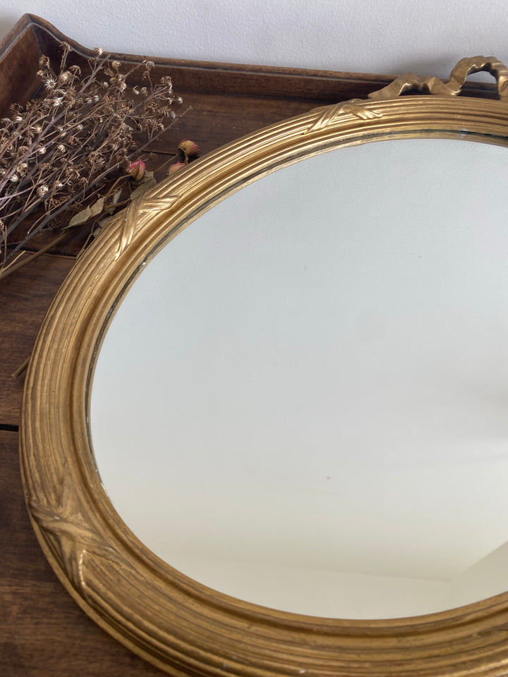 Miroir ovale en bois doré fronton noeud style Louis XVI