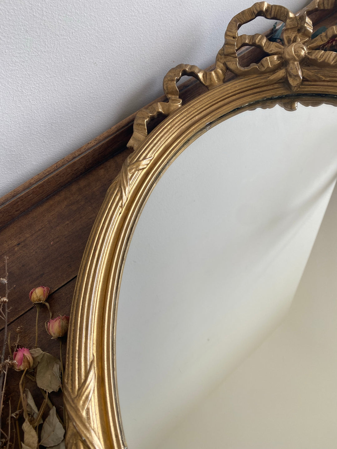 Miroir ovale en bois doré fronton noeud style Louis XVI