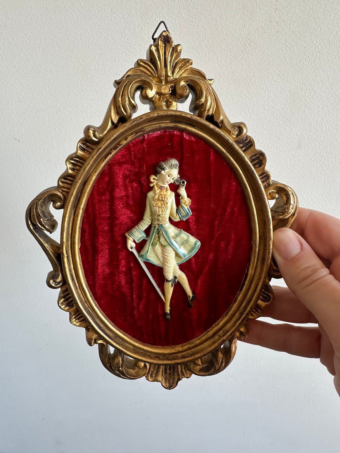 Figurine sur fond de velours rouge encadrement rococo doré