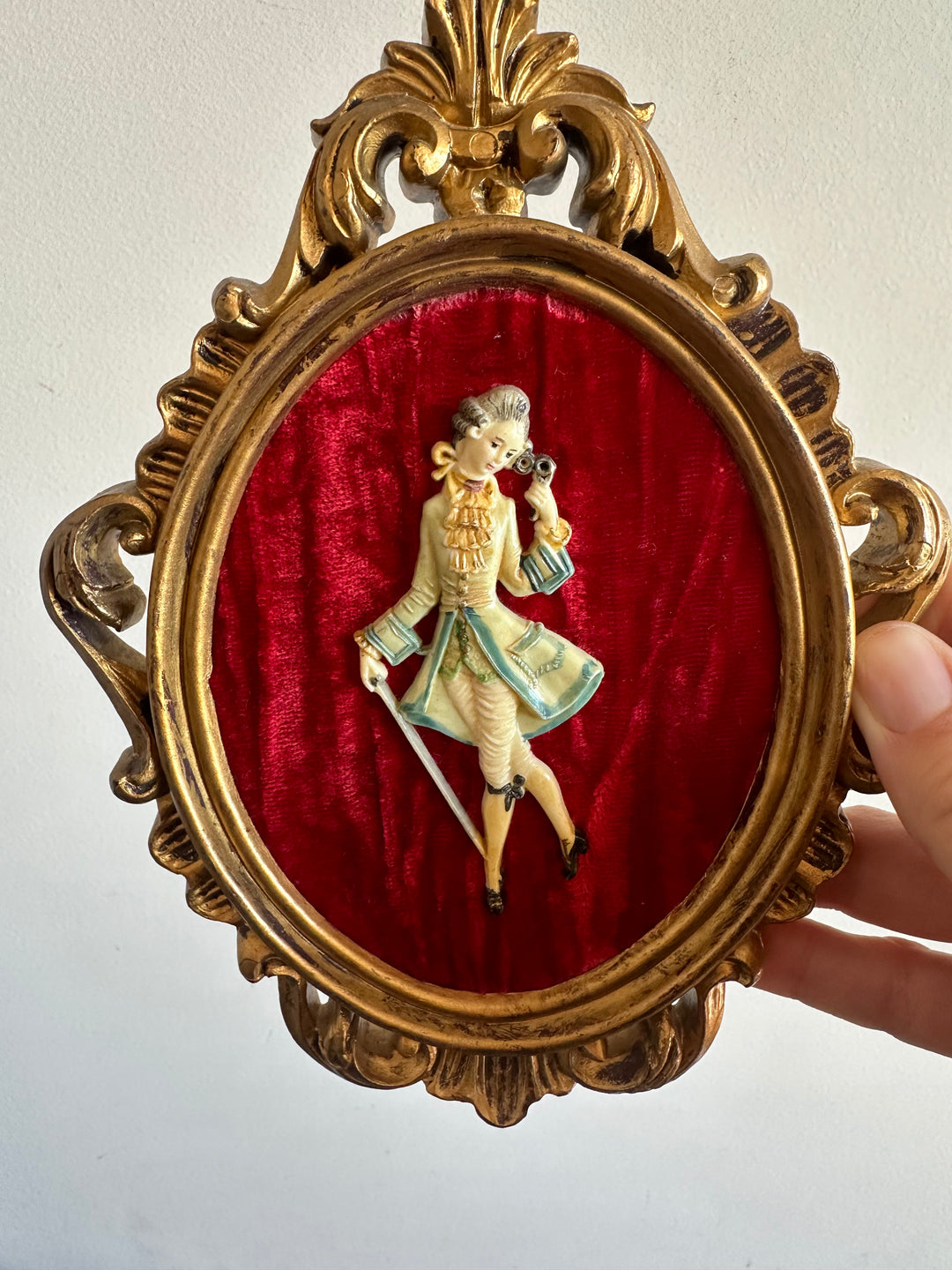 Figurine sur fond de velours rouge encadrement rococo doré