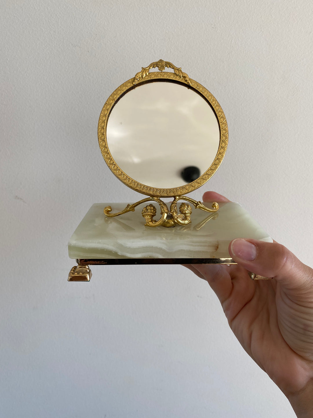 Miroir cerclé doré monté sur une plaque de pierre d’onyx