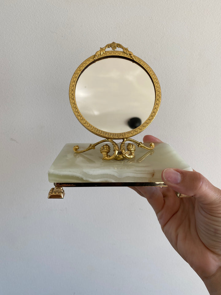 Miroir cerclé doré monté sur une plaque de pierre d’onyx